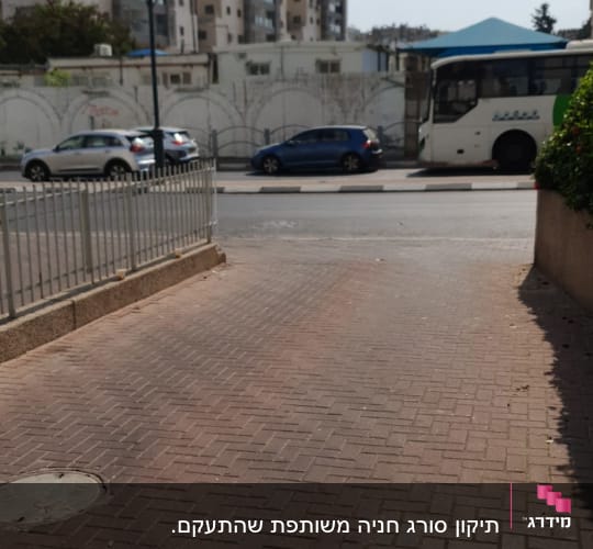 גדר מתכת לצד מדרכה מרוצפת בלבנים אדומות